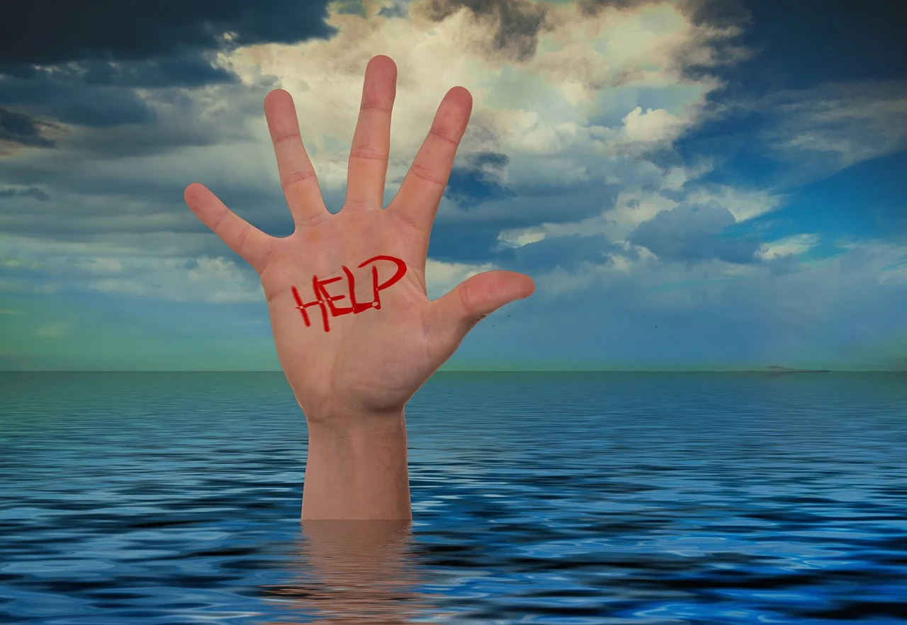 Z morza wystaje dłoń z napisem help