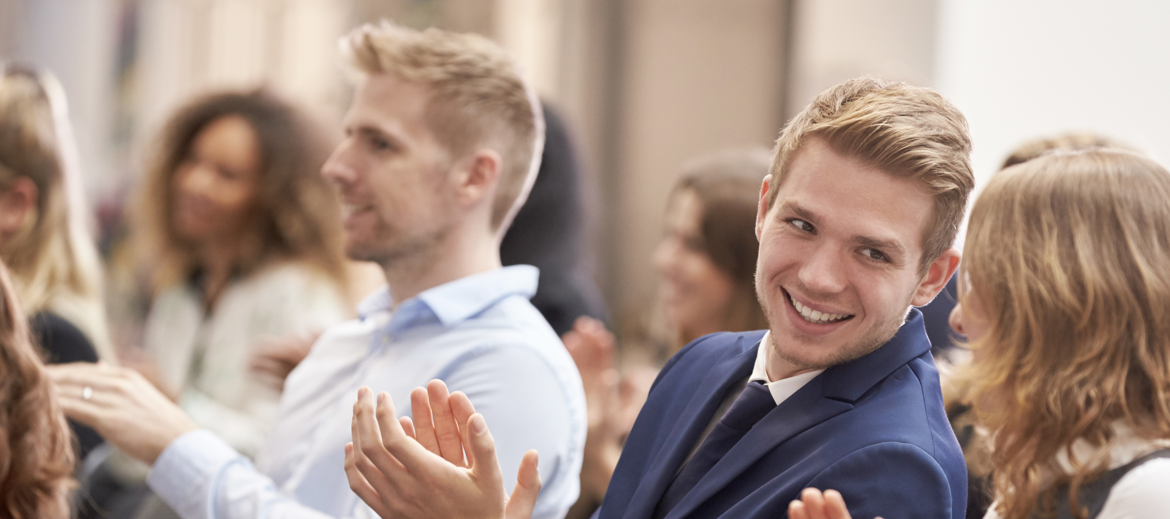 Uśmiechnięte osoby klaszczą, patrzą w bok