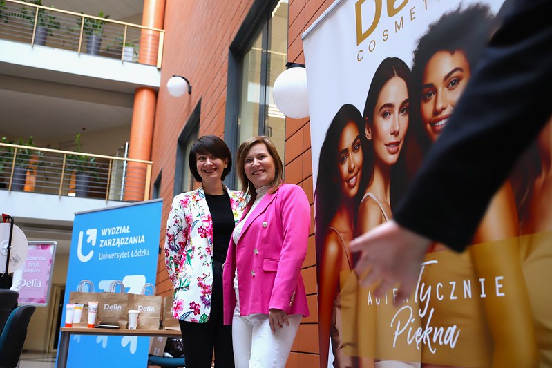 uczestnicy wydarzenia na tle roll-upa firmy