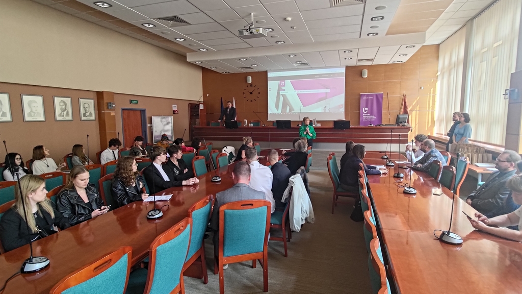 ludzie siedzą w sali i obserwują prezentacje 