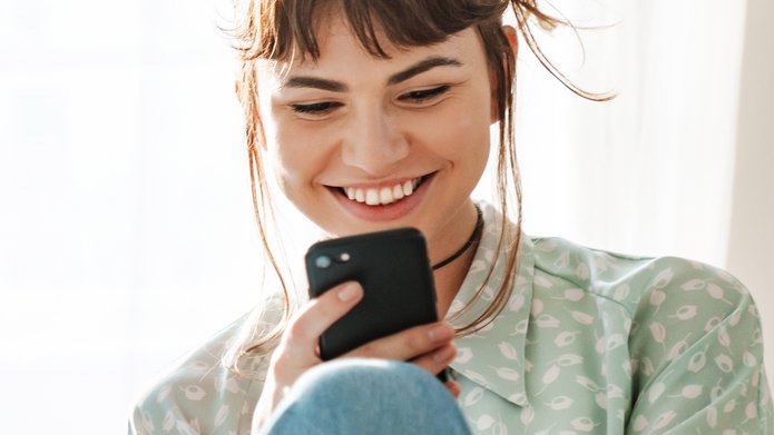 Uśmiechnięta dziewczyna czyta wiadomość na telefonie