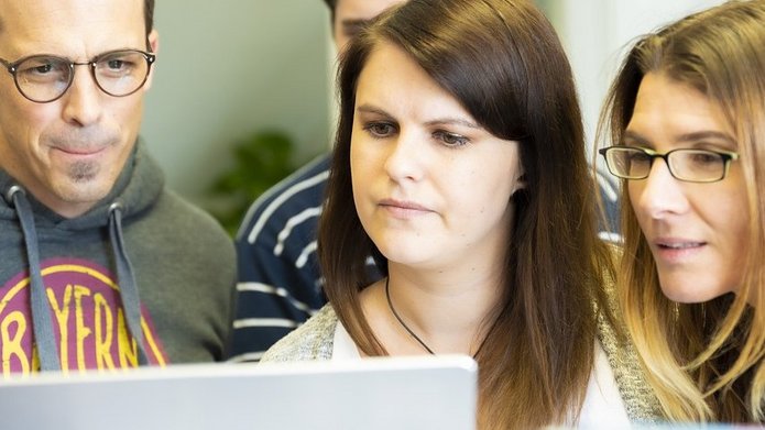 Grupa młody osób spoglądająca w ekran laptopa