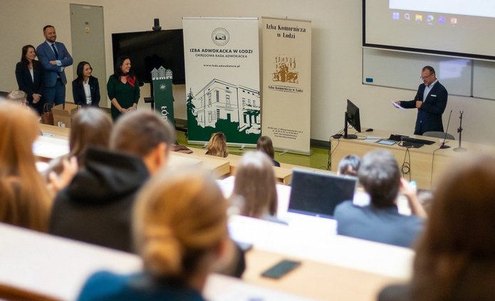 Grupa osób na auli uniwersyteckiej.