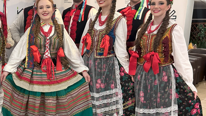 grupa tancerzy w strojach krakowskich na ściance firmy Łukasiewicz