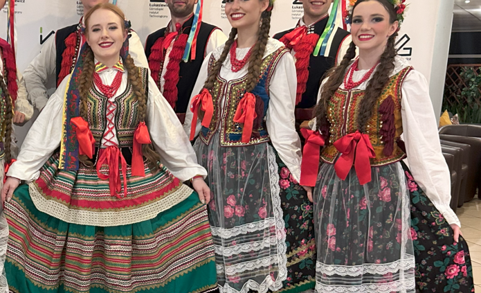 grupa tancerzy w strojach krakowskich na ściance firmy Łukasiewicz