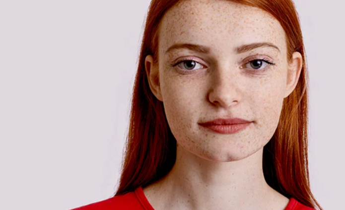 Piegowata ruda studentka na jasnym tle