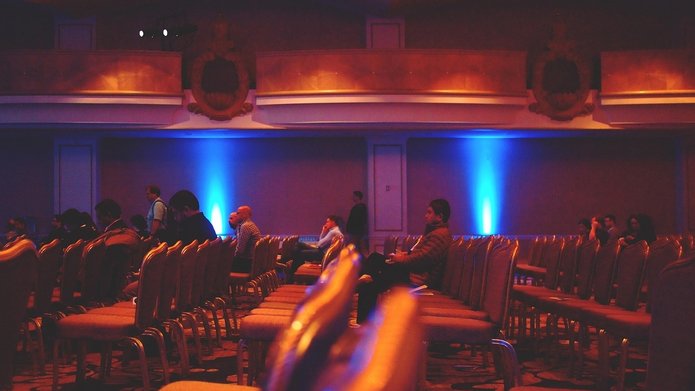 siedzące osoby na sali konferencyjnej
