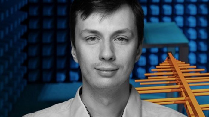 mgr inż. Maciej Ślot na tle anteny i dźwiękoszczelnego pokoju