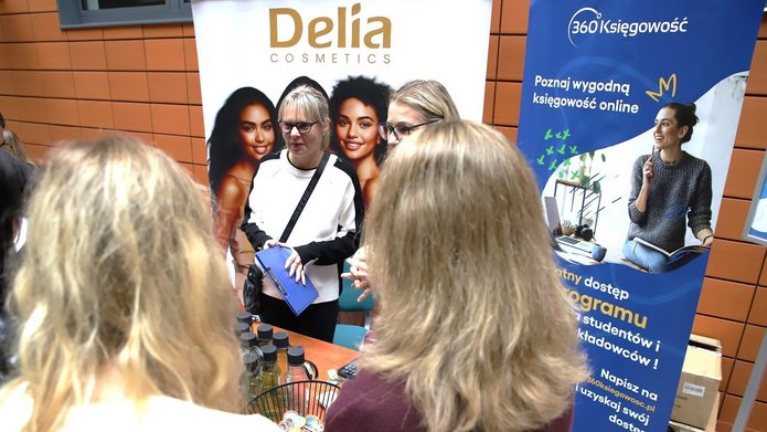 uczestnicy wydarzenia na stoisku na tle roll-upów firm