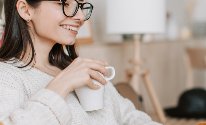 Młoda kobieta patrzy w komputer i uśmiecha się. Zdjęcie poglądowe.