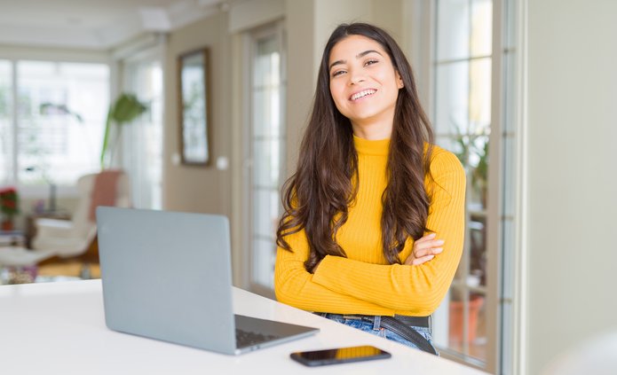 Dziewczyna przed laptopem, uśmiecha się do obiektywu