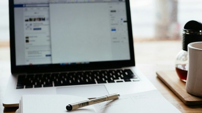 Element dekoracyjny: włączony laptop i otwarty notes leżący koło niego
