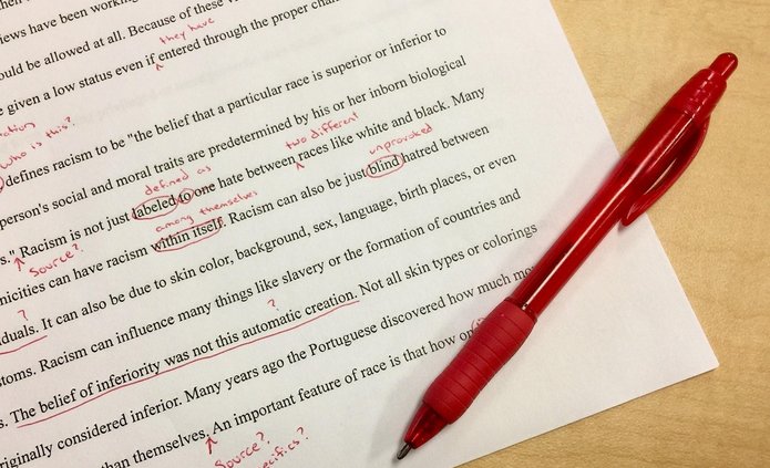 na kartce papieru drukowany tekst w języku angielskim i zaznaczone czerwonym długopisem błędy w tekście z noatkami