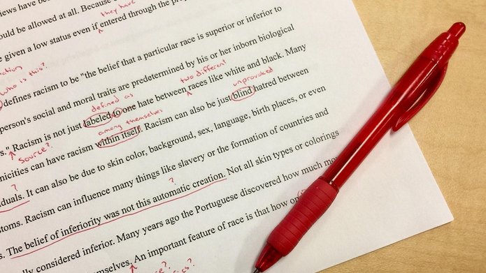 na kartce papieru drukowany tekst w języku angielskim i zaznaczone czerwonym długopisem błędy w tekście z noatkami
