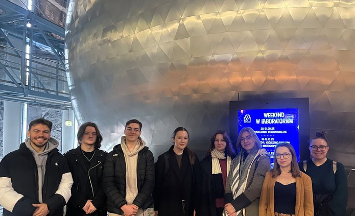 Na zdjęciu uczestnicy spotkania stojący przed kinem sferycznym. Zdjęcie przedstawia zarówno kobiety, jak i mężczyzn.