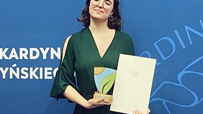 Osoba pozująca do zdjęcia z nagrodą w ręku