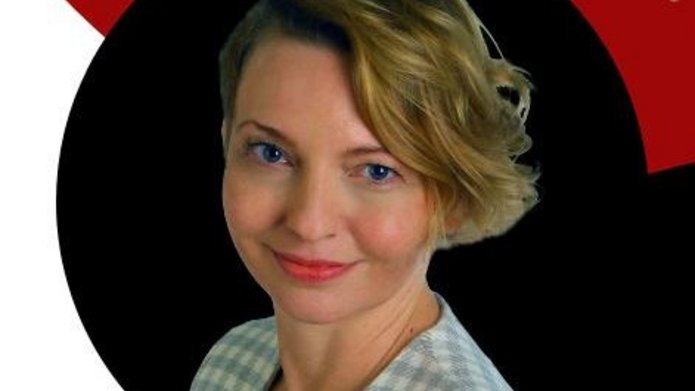 Kobieta o blond włosach w kraciastej marynarce.