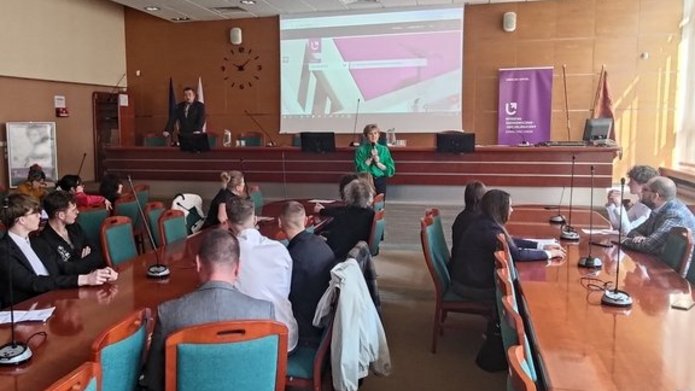 ludzie siedzą w sali i obserwują prezentacje 
