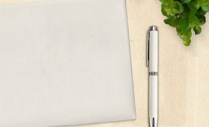 filiżanka z kawą, notatnik, długopis, zielona roślina