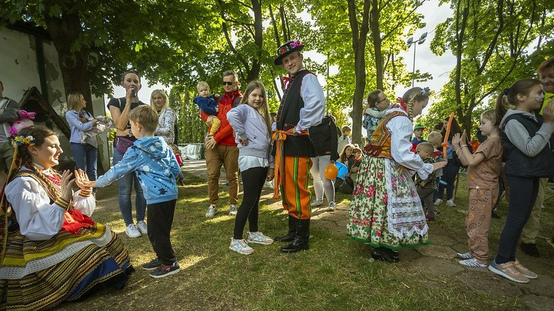 Dzieci i bawiący się z tancerzami AKADEMICKI ZESPÓŁ PIEŚNI I TAŃCA UŁ "KUJON", ubranymi w stroje ludowe
