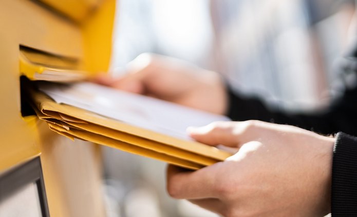 listonosz wkładający przesyłkę do skrzynki