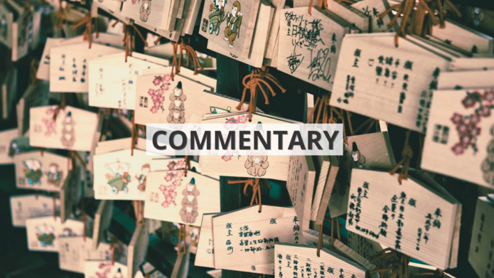 Drewniane tabliczki z życzeniami zapisanymi chińskimi znakami wiszące we wschodnioazjatyckiej świątyni z napisem ‘commentary’ / Wooden signs with wishes written in Chinese characters hanging in an East Asian temple with the inscription 'commentary'