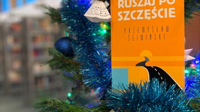Ubrana choinka, obok niej stoi książka "Ruszaj po szczęście".