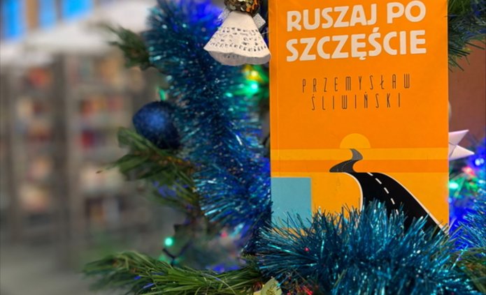 Ubrana choinka, obok niej stoi książka "Ruszaj po szczęście".