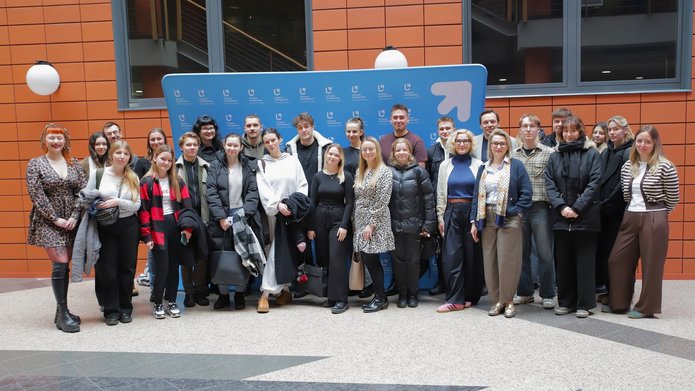 Grupa osób na tle ścianki Wydziału Zarządzania UŁ