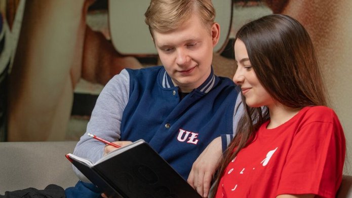 Student i studentka siedzą na kanapie i patrzą w notatnik