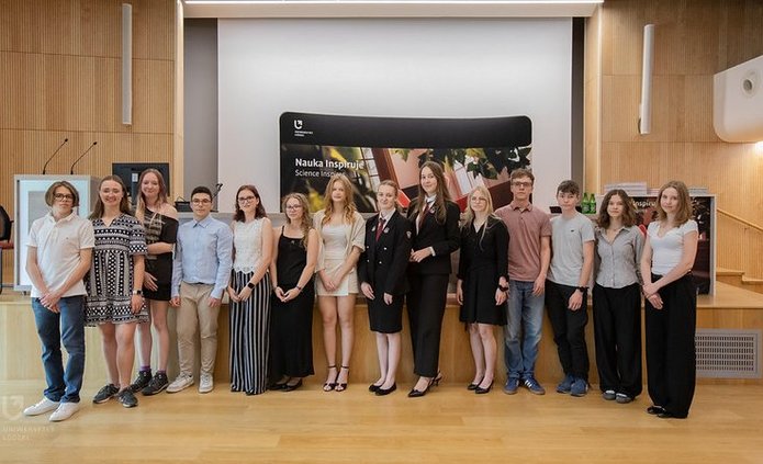 Grupa młodych osób - laureatów konkursu Laboratorium Innowacji - stoją w auli, pozując do zdjęcia