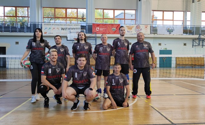Zdjęcie ośmioosobowego zespołu sekcji siatkówki na siedząco razem z trenerem Piotrem Jaworowiczem