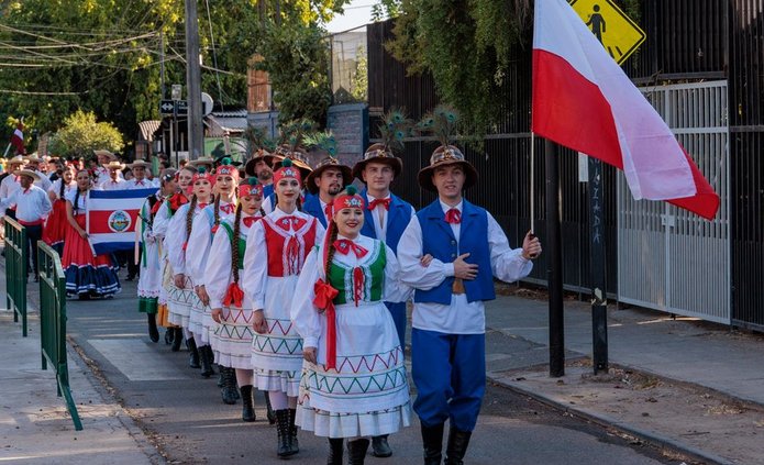 tancerze w strojach krośnieńskich niosący flagę Polski