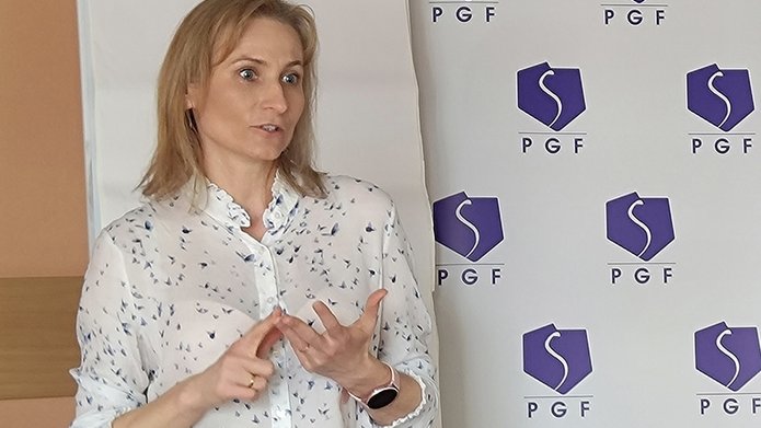 szkolenie pt. Autoprezentacja i radzenie sobie ze stresem - Polska Grupa Farmaceutyczna - 14.04.2025 - Prowadząca szkolenie stoi na tle rollupów PGF i Wydziału Ekonomiczno-Socjologicznego UŁ