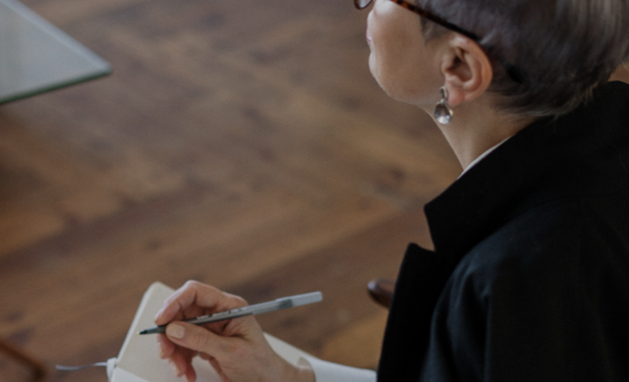 Zdjęcie poglądowe. Kobieta robi notatki w notesie.