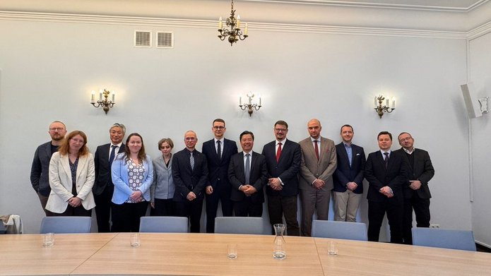 Zdjęcie grupowe grupy osób stojących przed stołem konferencyjnym na tle białej ściany