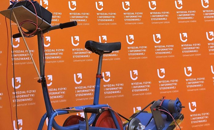 rower napędzany elektrycznie na tle pomarańczowej ścianki Wydziału