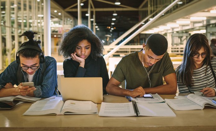 kolorowe zdjęcie przedstawiające studentów pracujących przy jednym stole w bibliotece