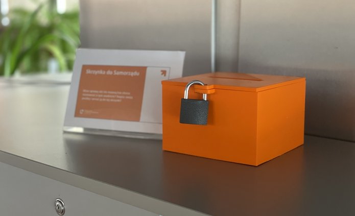 pomarańczowa skrzynka z kłódką stojąca na półce