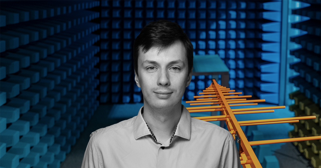 mgr inż. Maciej Ślot na tle anteny i dźwiękoszczelnego pokoju