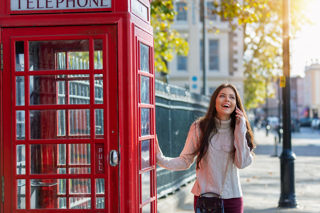 zdjęcie uśmiechniętej kobiety obok londyńskiej budki telefonicznej