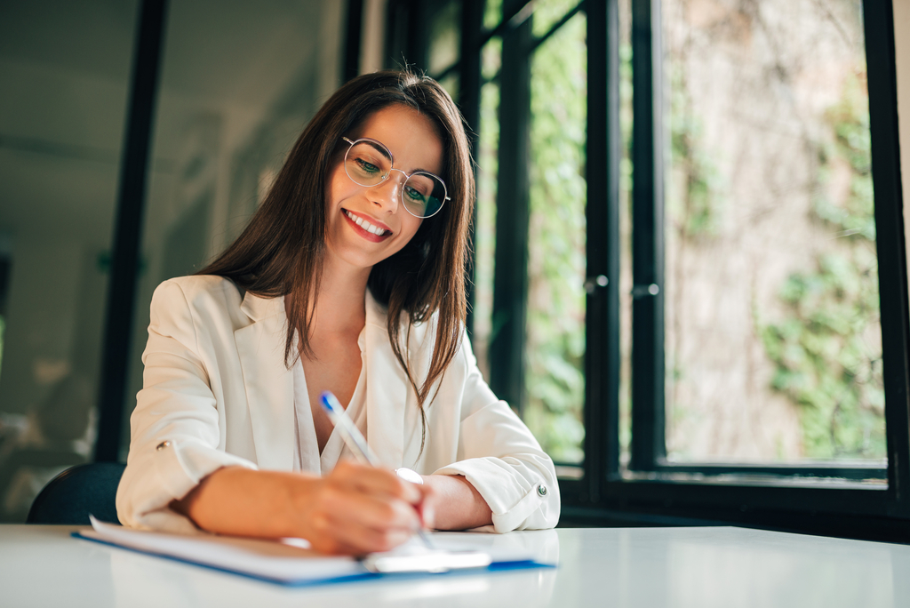 Zdjęcie uśmiechniętej kobiety piszącej egzamin