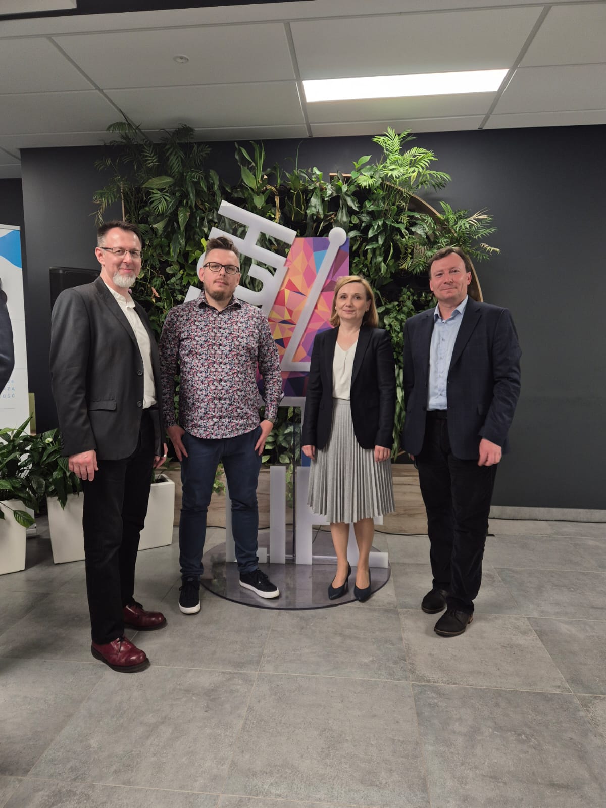 zdjęcie z konferencji, przedstawiające 4 osoby stojące obok siebie 