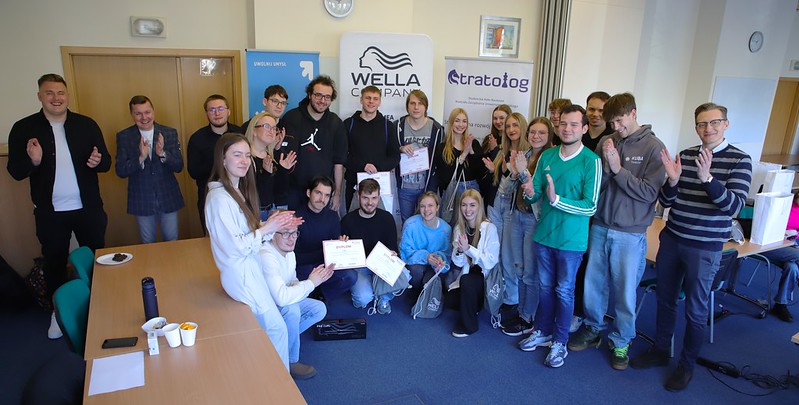 uczestnicy gry na tle roll-upów wydziału i sponsorów