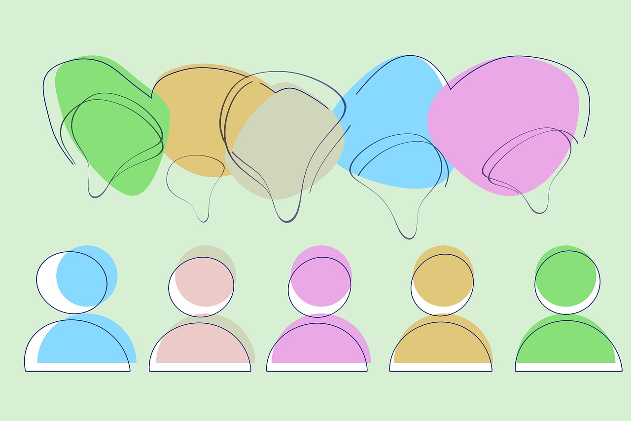 Na ilustracji widzimy pięć uproszczonych, kolorowych ikon przedstawiających postacie ludzkie – stylizowane na awatary. Każda z postaci ma inny kolor: niebieski, różowy, fioletowy, żółty i zielony. Nad każdą z tych postaci znajdują się kolorowe dymki rozmowy